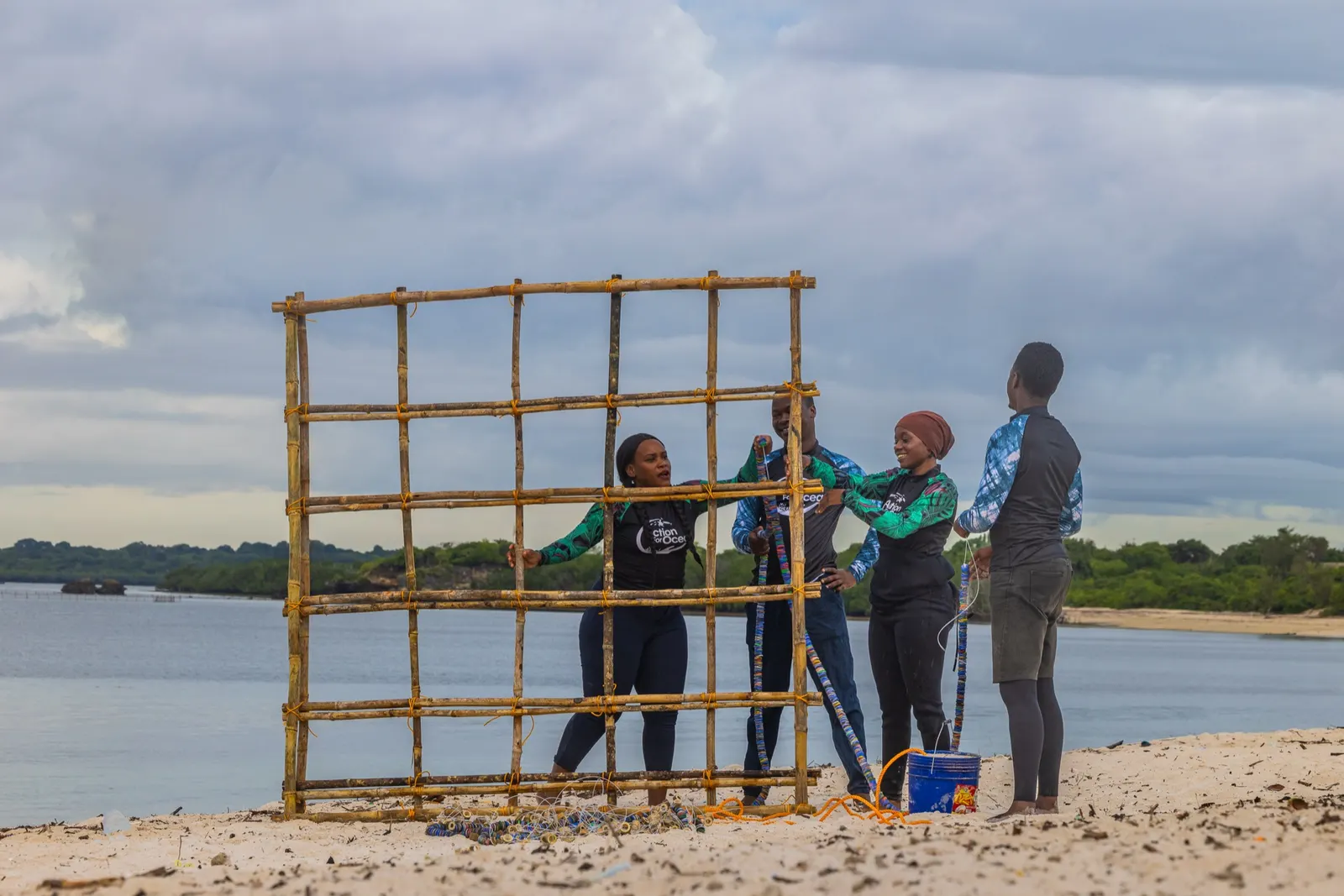 Field team assembling a wooden coral restoration frame on a beach